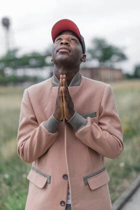 Young man praying with religious faith while standing outdoors model released Symbolfoto KMKF01463