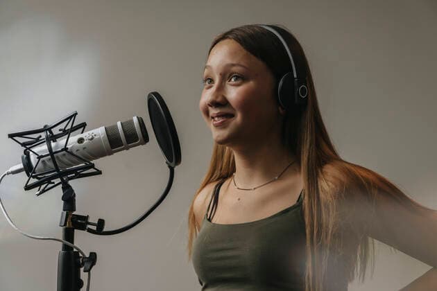 Tag der Musik am 21. Juni Close-up of smiling teenage girl singing over microphone against wall in recording studio model released Symbolfoto property released MFF06175