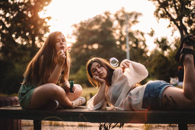 Girlfriends playing with bubbles while relaxing in park in summer CR_DMBE200923-468656-01 ,model released, Symbolfoto