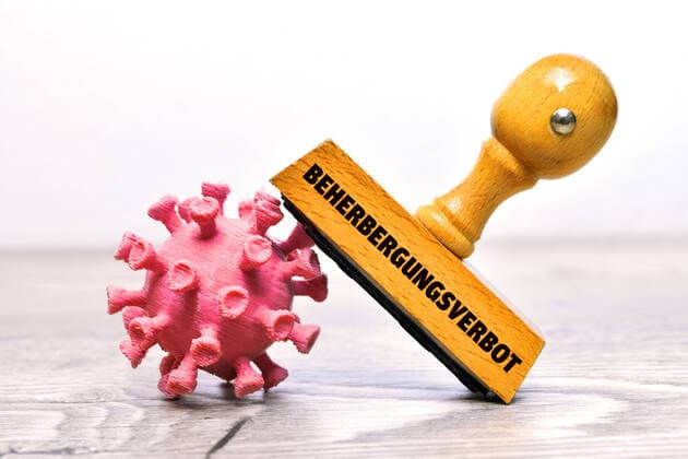 FOTOMONTAGE, Coronavirus und Stempel mit der Aufschrift Beherbergungsverbot