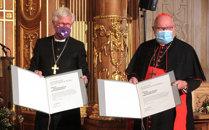 Der Ratsvorsitzender der Evangelischen Kirche in Deutschland (EKD), Heinrich Bedford-Strohm (li.), und der Muenchner Erzbischof Kardinal Reinhard Marx (re.) haben den Augsburger Friedenspreis erhalten. Beim Festakt am Samstagabend (10.10.2020) im Goldenen Saal des Rathauses in Augsburg sagte als Laudator der fruehere Bundespraesident Joachim Gauck, dass die beiden Kirchenmaenner Vorbilder oekumenischer Verstaendigung seien. Bedford-Strohm und Marx seien durch die christlichen Werte von Solidaritaet, Gerechtigkeit und Hoffnung ueber konfessionelle Unterschiede hinweg miteinander verbunden. Der mit 12.500 Euro dotierte Friedenspreis wird seit 1985 von der Stadt Augsburg und der bayerischen Landeskirche alle drei Jahre fuer Verdienste um ein Copyright: epd-bild AnnettexZoepf EDITORIAL USE ONLY