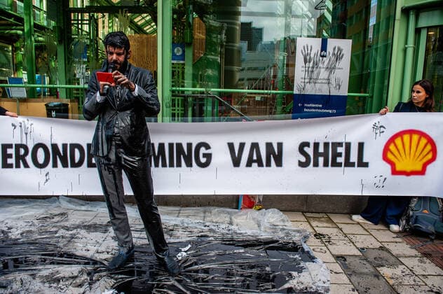 Bilder des Jahres 2020, News 10 Oktober News Themen der Woche KW42 News Bilder des Tages October 12, 2020, The Hague, Netherlands: A climate activist reading a statement while covered in fake oil..The Ministry of Economic Affairs (EZK) is organizing a Climate Day with the aim of inspiring The Netherlands with front runners to halve greenhouse gas emissions by 2030. Various climate groups are protesting against the participation of Marjan van Loon, director of Shell Netherlands. In the opening panel of the Climate Day. Several climate organizations showed up in front of the Ministry of Economic Affairs and Climate Policy building in The Hague against Shell as a guest of honor on the Climate Day . The climate activists wearing suits soaked in fake oil left their handprints on the facade of the EZK building. The Hague Netherla - ZUMAs197 20201012_zaa_s197_048 Copyright: xAnaxFernandezx