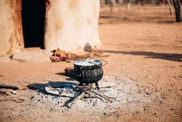 IMAGO Cultures of the world, Himba Volk in Namibia Namibia, Damaraland, iron pot boiling on a small fire in front a hut in a Himba village GEM000484