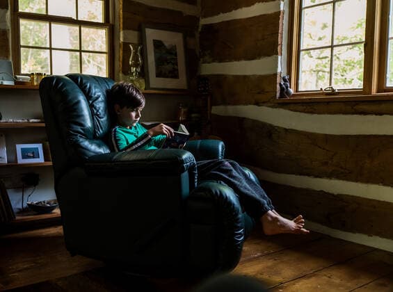 IMAGO Creative: Kulturelle Folgen der Pandemie: Gesundheitsbewußtsein und Alleinsein Young boy reading in leather recliner chair in rustic log cabin home. Buck Lake, ON, Canada CR_DOHO201016L-521069-01 ,model released, Symbolfoto