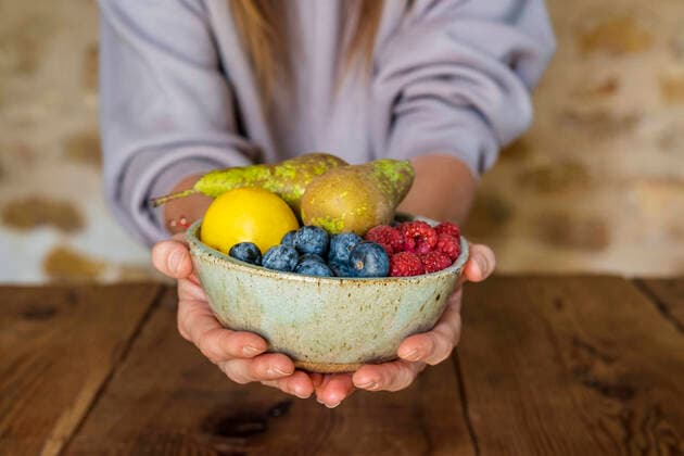 Creative Highlights Symbolfotos Close-up of various fruits in bowl held by female nutritionist at table model released Symbolfoto property released DLTSF01267