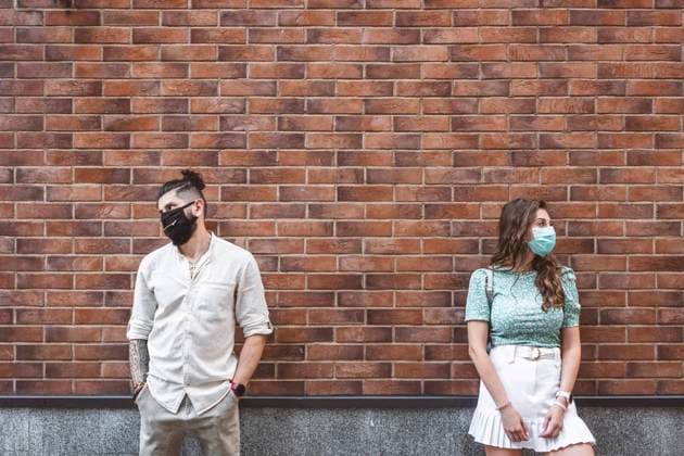 Creative Highlights Symbolfotos Sad couple in protective face masks standing against brick wall during coronavirus crisis model released Symbolfoto property released EYAF01341