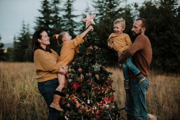 Parents carrying happy children decorating Christmas tree at countryside during sunset model released Symbolfoto GMLF00607