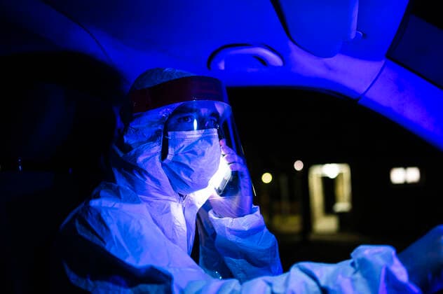 Male worker wearing workwear talking over mobile phone while driving ambulance at night model released Symbolfoto JCMF01423