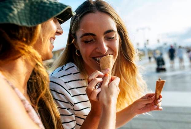 Smiling young woman feeding ice cream to sister while spending enjoying in city model released Symbolfoto MGOF04493