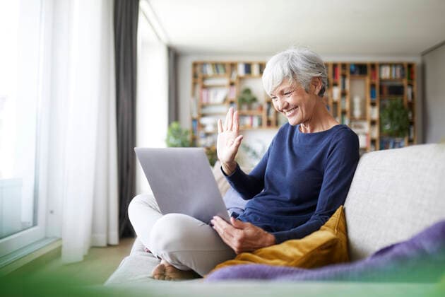 IMAGO Creative: Jahreszeit Winter, Couching Senior woman doing high five on video call while using laptop at home model released Symbolfoto property released RBF07840