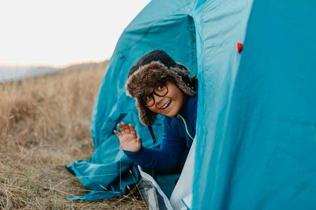 Smiling boy waving hand while sitting in tent model released Symbolfoto VABF03483