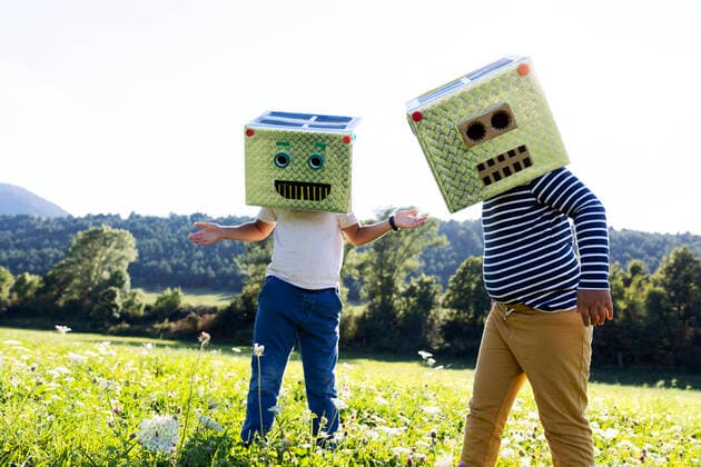 IMAGO Kreativ: Bruderschaft Boys covered face with smiling and robot box while playing in meadow model released Symbolfoto VABF03515