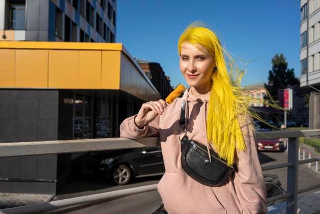 Dyed yellow hair woman eating ice cream while standing on bridge during sunny day model released Symbolfoto VPIF03116