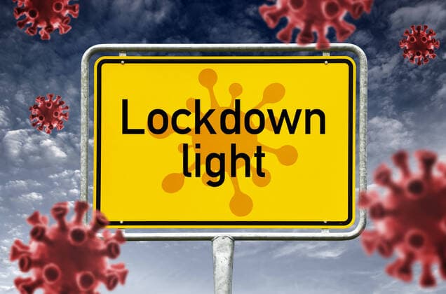 FOTOMONTAGE, Ortsschild mit Schriftzug Lockdown light und Corona-Viren, Corona-Lockdown