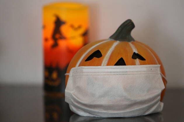 Symbolbild zum Thema Halloween in Zeiten der Corona-Pandemie, ein Kuerbiskopf aus Porzellan mit Mundschutz, dahinter eine Kerze, Lampe Symbolbild, Halloween, Corona am 27.10.2020 in Siegen Deutschland.