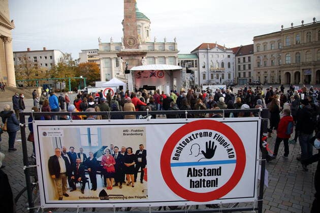 Konzertbesucher und ein Banner mit einem Gruppenfoto der AfD-Fraktion sowie der Aufschrift Rechtsextreme Flügel-AfD Abstand halten! bei einem Protestkonzert gegen die Wahl des neuen AfD-Fraktionsvorsitzenden auf dem Alten Markt am Brandenburger Landtag in Potsdam, 27. Oktober 2020. Protestkonzert Flügel statt Flügel in Potsdam