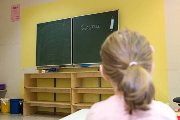 Kind in einem Klassenraum einer Grundschule mit dem Wort Corona