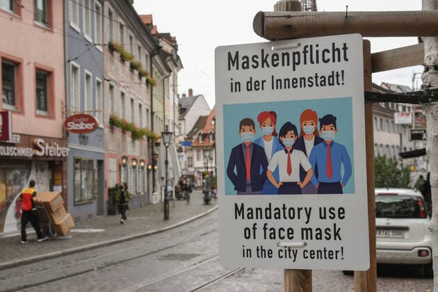 Maskenpflicht. Hinweistafel in Freiburg. Seit Montag geht Deutschland in einen Teil-Lockdown bis Ende November. Bund und Laender haben sich auf gemeinsame Massnahmen geeinigt, um die Zweite Welle einzudaemmen. Hotels, Restaurants, Kinos, Theater, Freizeiteinrichtungen muessen bis Ende November schliessen, Kontakte und Reisen weitgehend minimiert werden. Vielerorts gilt Maskenpflicht.