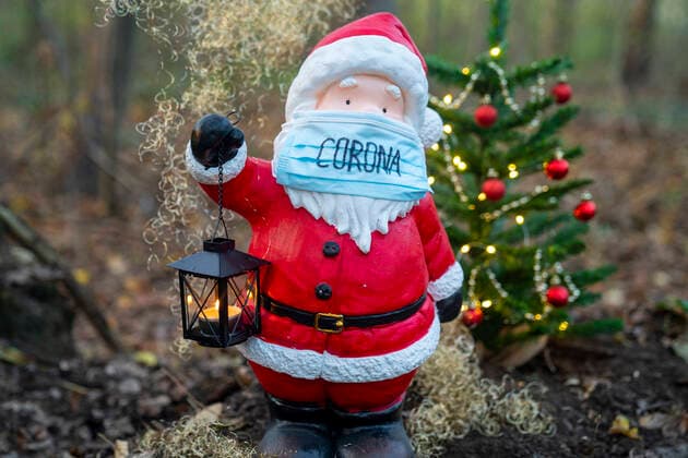 Symbolfoto, Weihnachtsmann mit Corona Mund-Nasenschutz Symbolbild Nikolaus mit Maske. Die Adventszeit und Weihnachten scheinen dieses Jahr unter starken Corona und moeglichen Kontakt Beschraenkungen stattzufinden. Hier ein Weihnachtsmann mit Corona Gesichtsmaske und Weihnachtsbaum im Wald - Deutschland