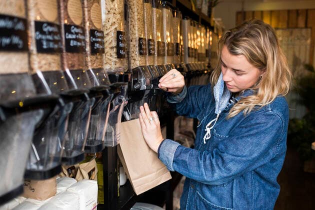 Young blond woman wearing face mask, shopping in waste free wholefood store. United Kingdom,Young blond woman wearing face mask, shopping in waste free wholefood store.  Young blond woman wearing face mask, shopping in waste free wholefood store.