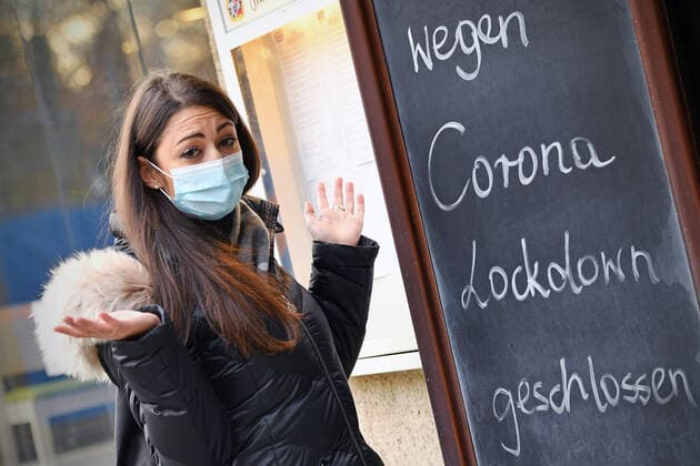Themenbild: Coronavirus Pandemie Folgen fuer die Gastronomie. Eine Junge Frau steht mit Mundschutz,Maske ratlos vor einem Schild: WEGEN CORONA LOCKDOWN GESCHLOSSEN, Geschlossenes bayerisches Restaurant am Sendlinger Tor in Muenchen. Seit dem 2.November muss wegen dem Lockdown light die Gastronomie geschlossen bleiben, Schliessung-Folge der Corona Pandemie,Lockdown,Shutdown,Inzidenzwert. MODEL RELEASED!
