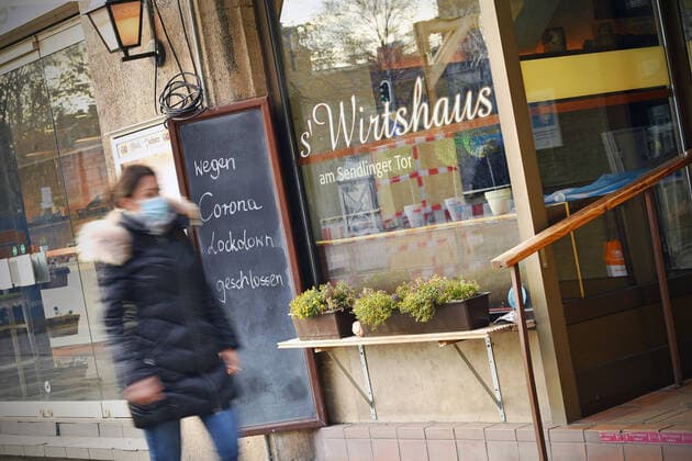 Themenbild: Coronavirus Pandemie Folgen fuer die Gastronomie. Schild am Wirtshaus am Sendlinger Tor; WEGEN CORONA LOCKDOWN GESCHLOSSEN, eine junge Frau,Passantin geht vorbei. Geschlossenes bayerisches Restaurant am Sendlinger Tor in Muenchen. Seit dem 2.November muss wegen dem Lockdown light die Gastronomie geschlossen bleiben, Schliessung-Folge der Corona Pandemie,Lockdown,Shutdown,Inzidenzwert. MODEL RELEASED!