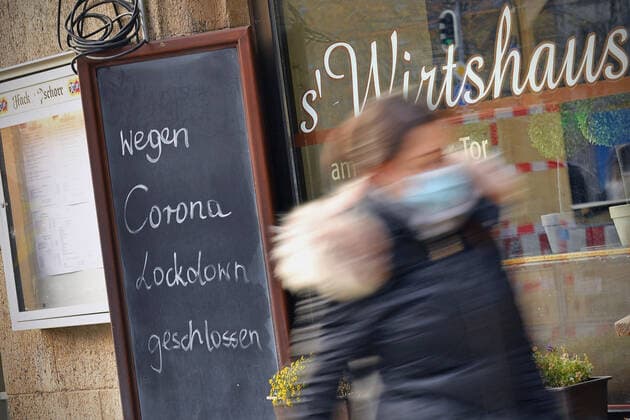 Themenbild: Coronavirus Pandemie Folgen fuer die Gastronomie. Schild am Wirtshaus am Sendlinger Tor; WEGEN CORONA LOCKDOWN GESCHLOSSEN, eine junge Frau,Passantin geht vorbei. Geschlossenes bayerisches Restaurant am Sendlinger Tor in Muenchen. Seit dem 2.November muss wegen dem Lockdown light die Gastronomie geschlossen bleiben, Schliessung-Folge der Corona Pandemie,Lockdown,Shutdown,Inzidenzwert. MODEL RELEASED!