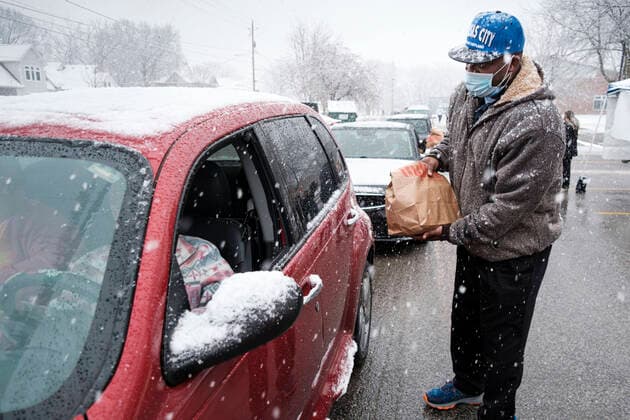 November 23, 2020, Des Moines, Iowa, U.S: A volunteer hands a bag of food to a motorist in line during a Thanksgiving food distribution at a park in Des Moines during a snowstorm. The food distribution was organized by Urban Dreams, a community empowerment NGO in central Des Moines, and the NAACP. The food was provided by Hy-Vee, a regional grocery store chain based in Des Moines. They had about 450 meals available. A spokesperson for Hy-Vee said the company was giving away more than 20,000 Thanksgiving meals this year. The Food Bank of Iowa said food insecurity in Des Moines has doubled since the start of the Coronavirus pandemic. Des Moines U.S. - ZUMAk94_ 20201123_zaf_k94_020 Copyright: xJackxKurtzx