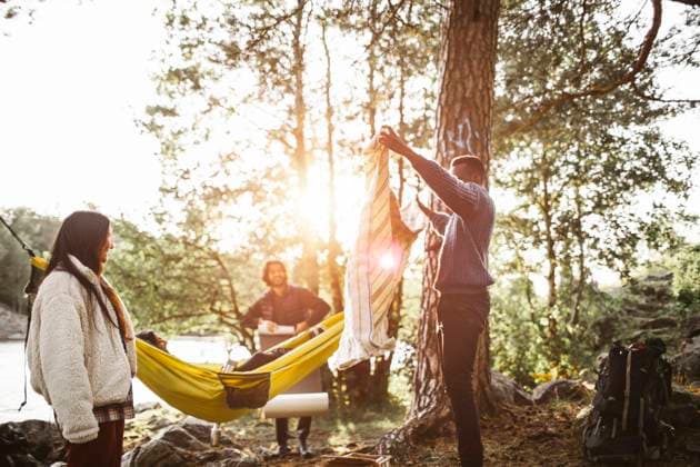 Male showing picnic blanket to friends in forest during vacation, MA82632, Sweden, Stockholm, model released