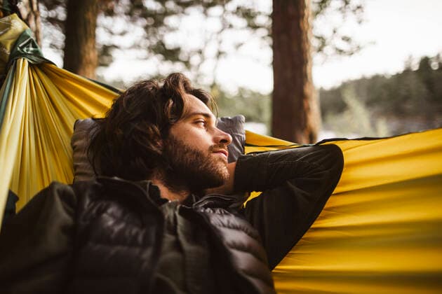 IMAGO Creative: Klimawandel - Nachhaltiges Reisen Contemplating man looking away while lying over hammock in forest, MA82659, Sweden, Stockholm, model released
