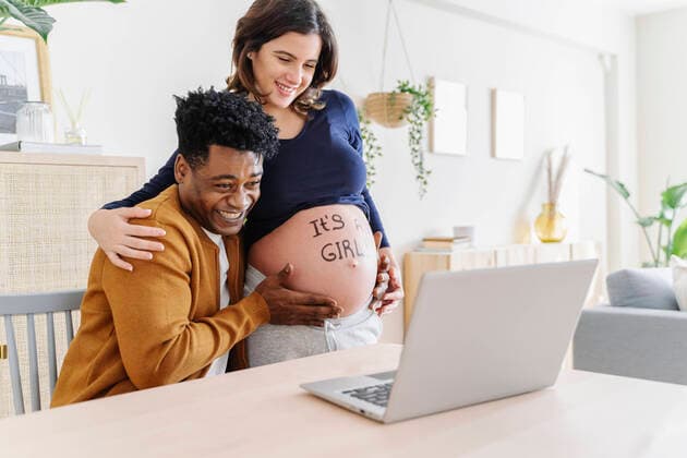 Husband and pregnant wife celebrating ultrasound results in front of a laptop, with a phrase written on her belly that it is a girl. Parenthood concept Sant Cugat del Vallès, CT, Spain CR_KTUU201128-569171-01 ,model released, Symbolfoto ,property released