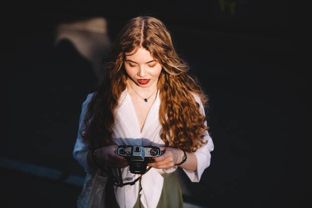 IMAGO Creative, Sommer, Schatten-Plätze bei Hitze Young woman holding analog film camera while standing in city CR_DMBE201207-477666-01 ,model released, Symbolfoto