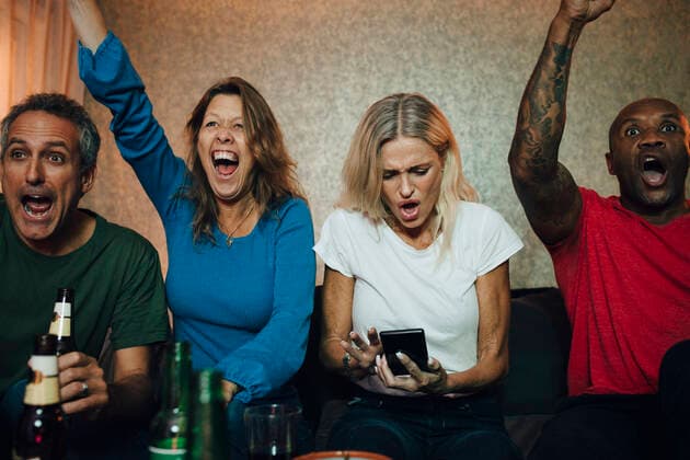 Happy friends cheering while watching sports on TV in living room, MA82796, Sweden, Stockholm, model released, property released Copyright: xMaskotx