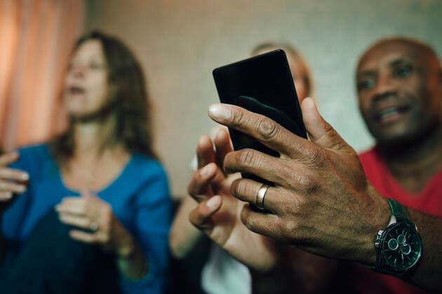 Smiling man showing mobile phone to women during sporting event, MA82797, Sweden, Stockholm, model released, property released Copyright: xMaskotx