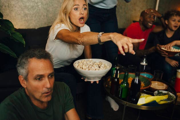 Woman with mouth open gesturing by family while eating popcorn during sporting event, MA82841, Sweden, Stockholm, model released, property released Copyright: xMaskotx