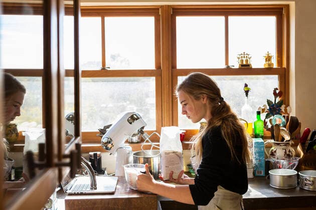IMAGO Creative: Haushaltsgeräte - Küchenmaschine Teenage girl in a kitchen following a baking recipe on a laptop. Teenage girl in a kitchen following a baking recipe on a laptop.  Teenage girl in a kitchen following a baking recipe on a laptop.