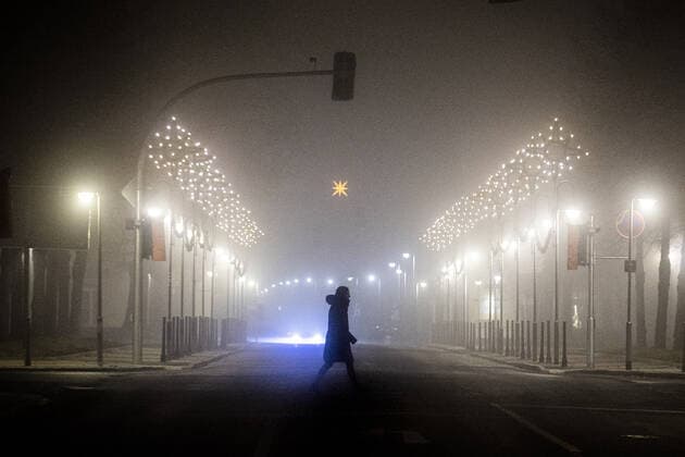 Eine Frau laeuft entlang einer mit Weihnachtsbeleuchtung geschmueckten Strasse im Nebel in Niesky, 11.12.2020. Die saechsische Landesregierung hat einen Lockdown ab Montag, dem 14.12. angekuendigt, um die Infektionszahlen der Corona-Pandemie vor Weihnachten zu senken. Dazu gehoert auch eine Ausgangssperre von 22 Uhr bis 6 Uhr morgens. Niesky Deutschland