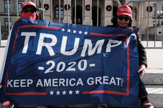 December 12, 2020, Atlanta, Georgia, USA: At a pro-Trump rally in Atlanta, two demonstrators hold a flag that reads TRUMP 2020 KEEP AMERICA GREAT on the steps of the Georgia State Capitol. The rally took place one day after the U.S. Supreme Court rejected a lawsuit filed by the state of Texas, asking the court to overturn the election results in Georgia, Pennsylvania, Michigan, and Wisconsin; four battleground states that were won by President-Elect Joe Biden in the 2020 presidential election. Atlanta USA - ZUMAb165 20201212_znp_b165_004 Copyright: xJohnxArthurxBrownx