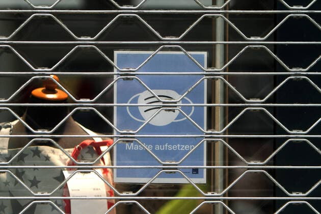 Schild mit Piktogramm Maskenpflicht hängt im Schaufenster eines mit Rolltor verschlossenen Geschäft s in der Innenstadt von Köln, Nordrhein Westfalen, Deutschland