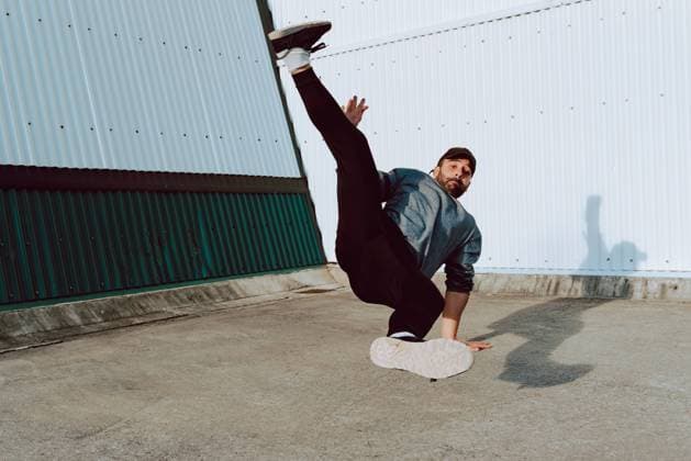 IMAGO Creative: Sport in der Stadt Attractive guy performing handstand and looking at camera while dancing near wall of modern building on city street, Model released Copyright: xAlbertoxMenendezx MR