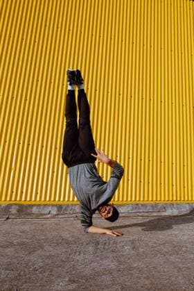 Attractive guy performing handstand and while dancing near wall of modern building on city street, Model released Copyright: xAlbertoxMenendezx MR
