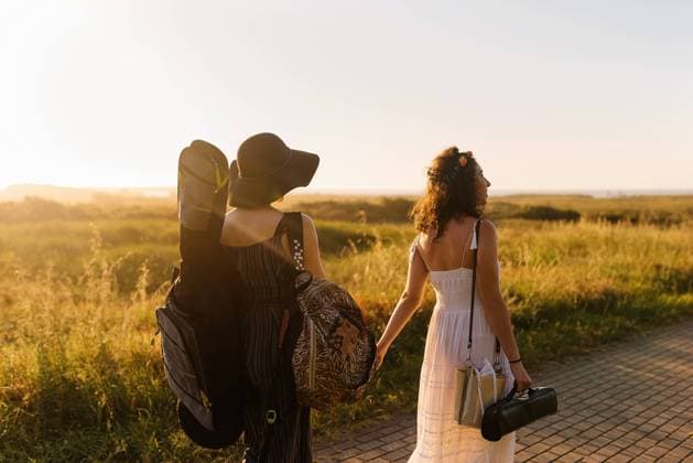 IMAGO Creative: Sommer, Abendspaziergang Back view of couple of girlfriends walking with musical instruments and holding hands while enjoying sunset in summer, Model released Copyright: xAlbertoxMenendezx MR
