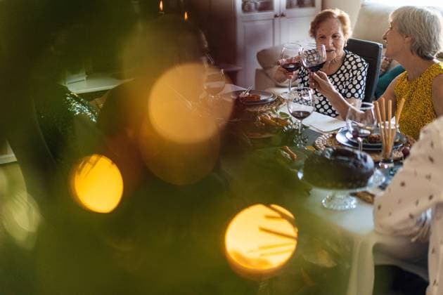 Diversity, Weihnachten Happy mature friends gathering at festive table near shining Christmas tree and clinking wineglasses while celebrating Christmas eve together, Model released Copyright: xAlvaroxSanchezx MR