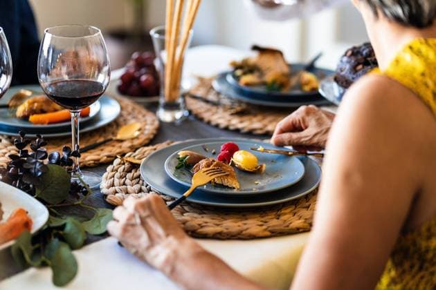 Side view of crop unrecognizable female at table with delicious chicken and potato near glass of red wine during festive event, Model released Copyright: xAlvaroxSanchezx MR