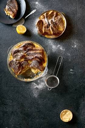 Top view of traditional bread pudding with custard, served with aromatic orange zest butter and powdered sugar on dark background Copyright: xAnastasiaxNurullinax Model Released