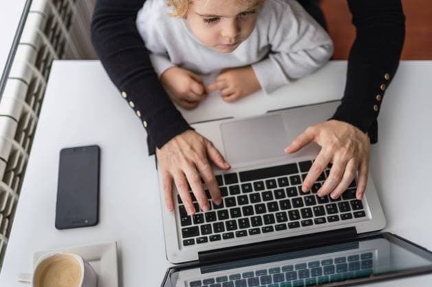 IMAGO Creative: Kreative Renaissance -- der junge Entrepreneur From above of crop anonymous female remote employee holding curious little child on knees while sitting at table and working with laptop at home Copyright: xAngelxSantamariax Model Released