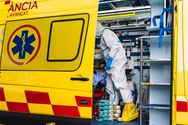 Side view of anonymous doctor in protective suit standing in ambulance car near opened door with equipment and examining patient with virus infection, Model released Copyright: xAparicioxFebrerx MR