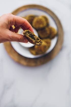 IMAGO Nature: Unsere Erde, Klimawandel, Ern?hrung, Pflanzen der Zukunft, Linse Top view of hand grabbing a lentil falafel from a dish served with yogurt sauce on a wooden table Copyright: xCoralxCastrox Model Released