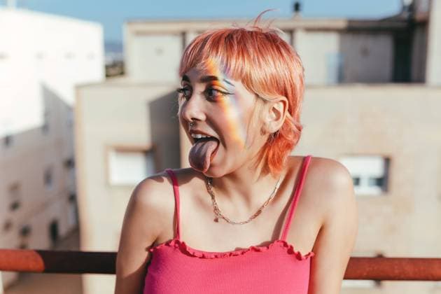 IMAGO Creative, Lifestyle, Barbiecore Cheerful female in summer wear looking away while sticking tongue out and leaning on railing in city Copyright: xDanixNavarrox Model Released