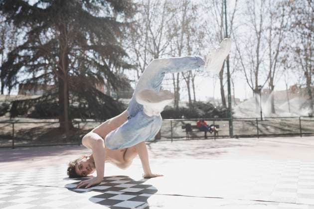 Young athletic guy in jeans practicing break dance in park in sunny weather Copyright: xDavidxGailx Model Released